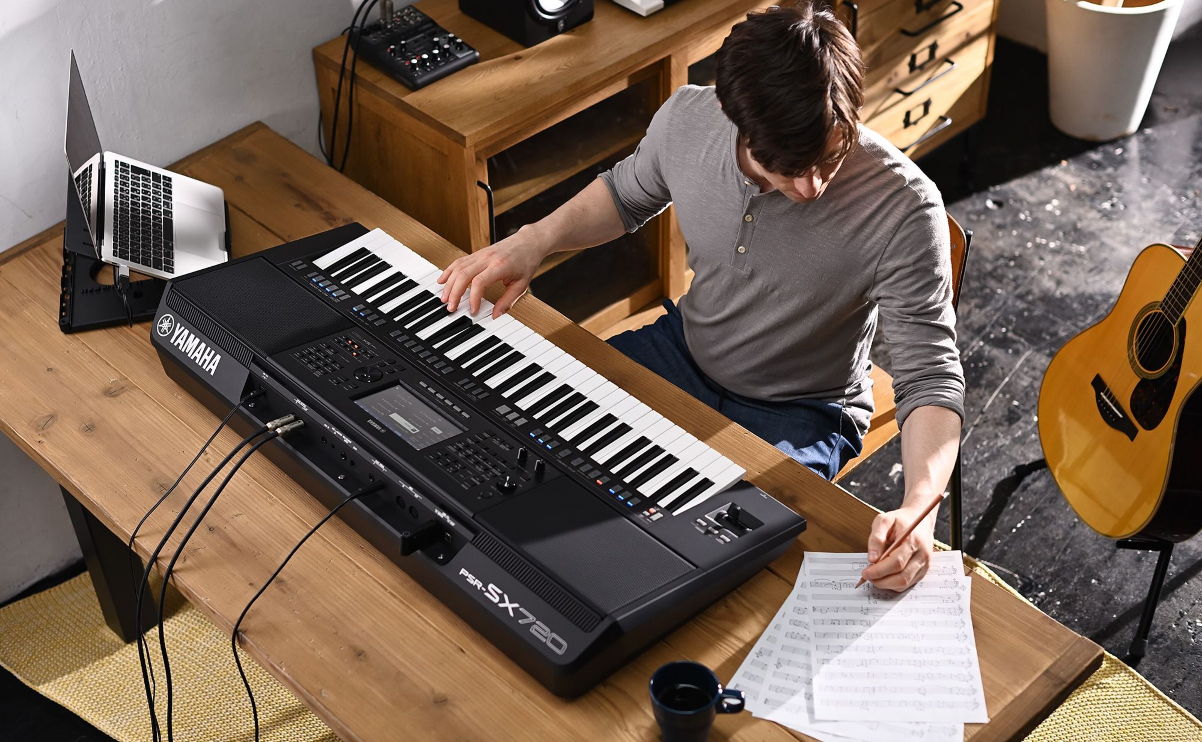 Photo of a person writing on sheet music while playing the Yamaha Arranger Workstation PSR-SX720