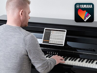 A person playing the piano by placing the smart device on a music stand and displaying sheet music on the Yamaha Smart Pianist app screen, and the Smart Pianist app icon