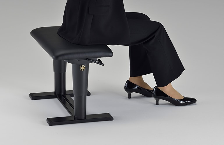 A person is sitting on a concert piano bench