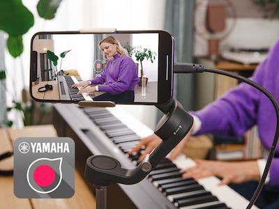 Una vista del icono de la aplicación Yamaha Rec'n'Share y una persona grabando un vídeo con su teléfono inteligente tocando